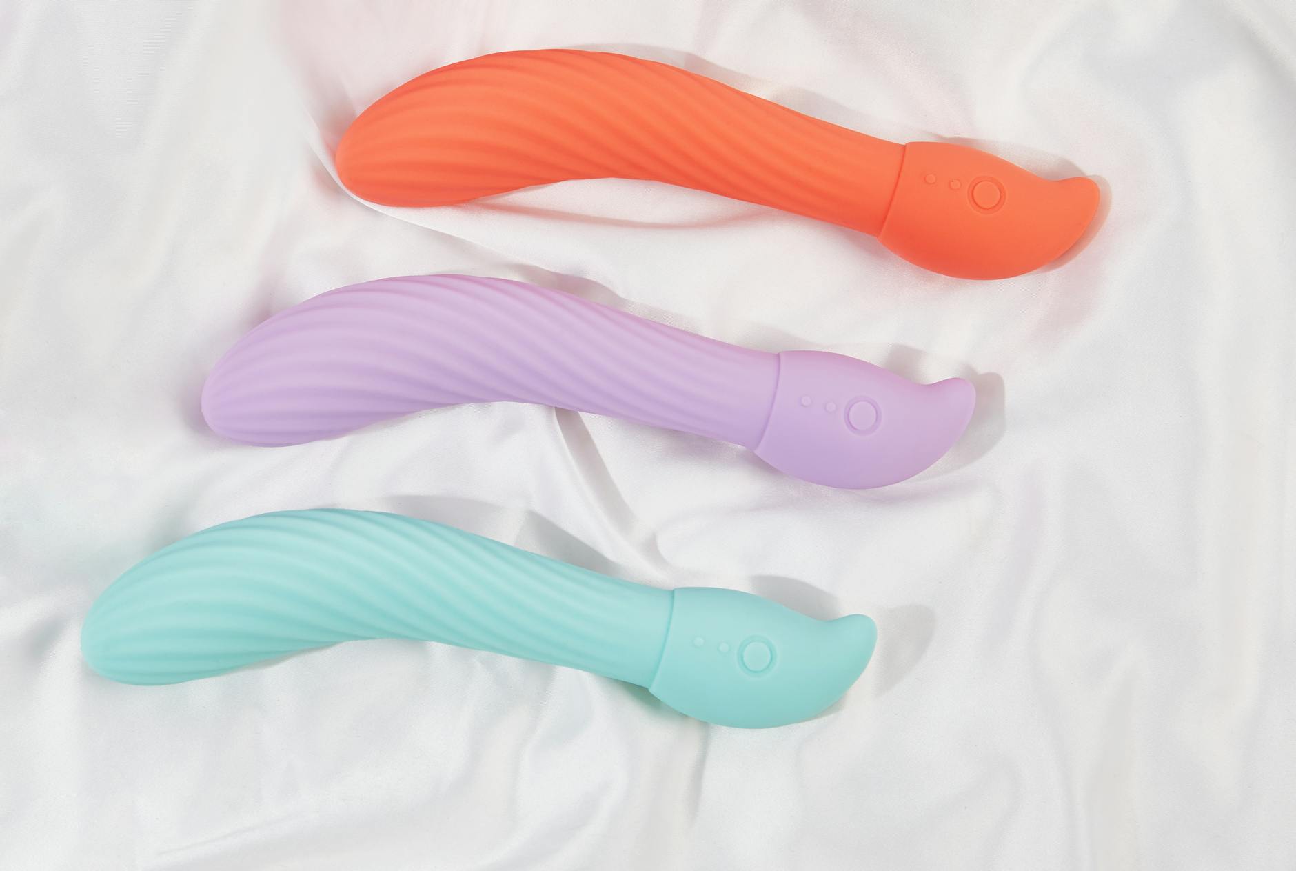 Blue silicone clitoral vibrator held in hand against purple background