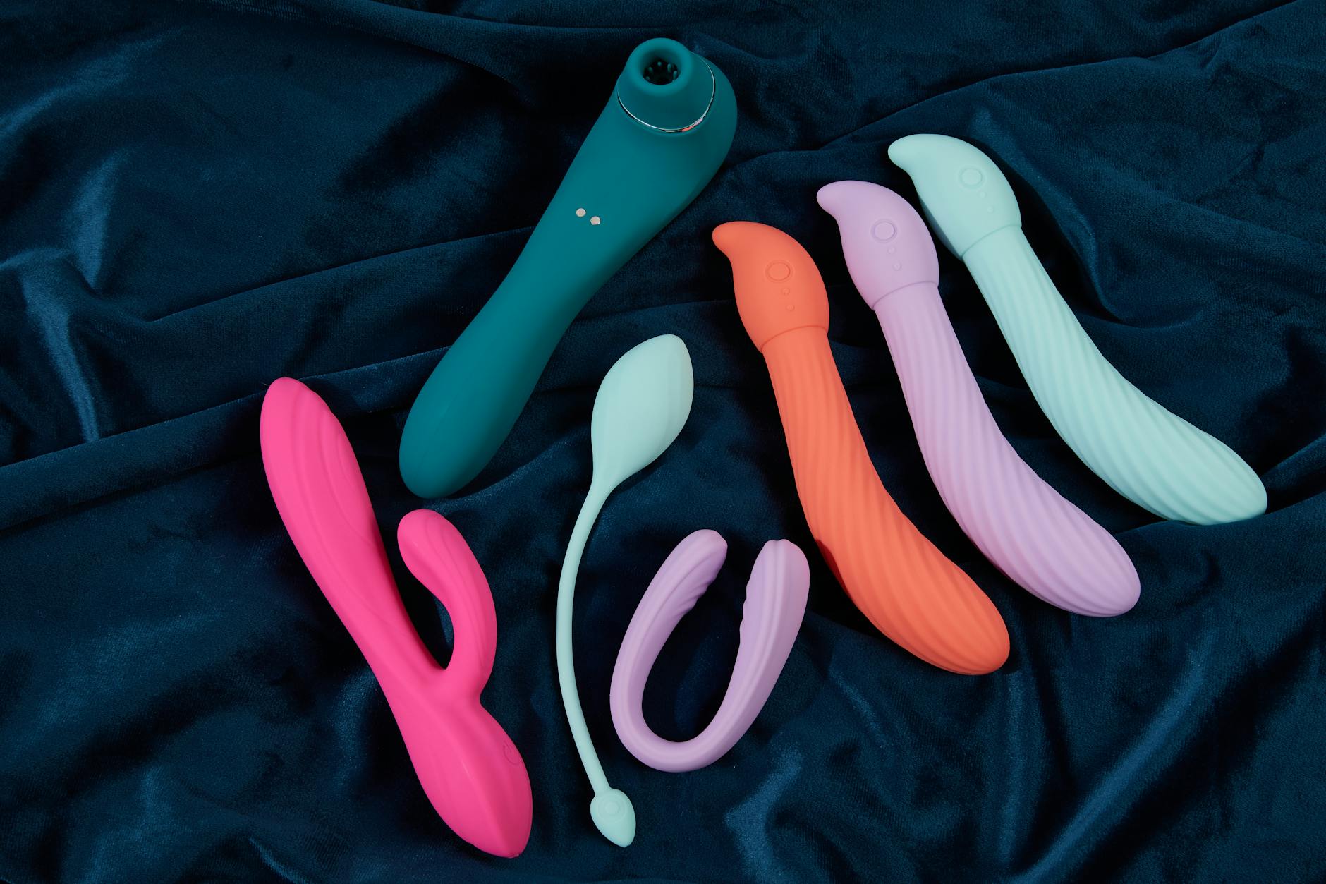 Hand holding an orange vibrator against a purple backdrop, symbolizing pleasure and intimacy