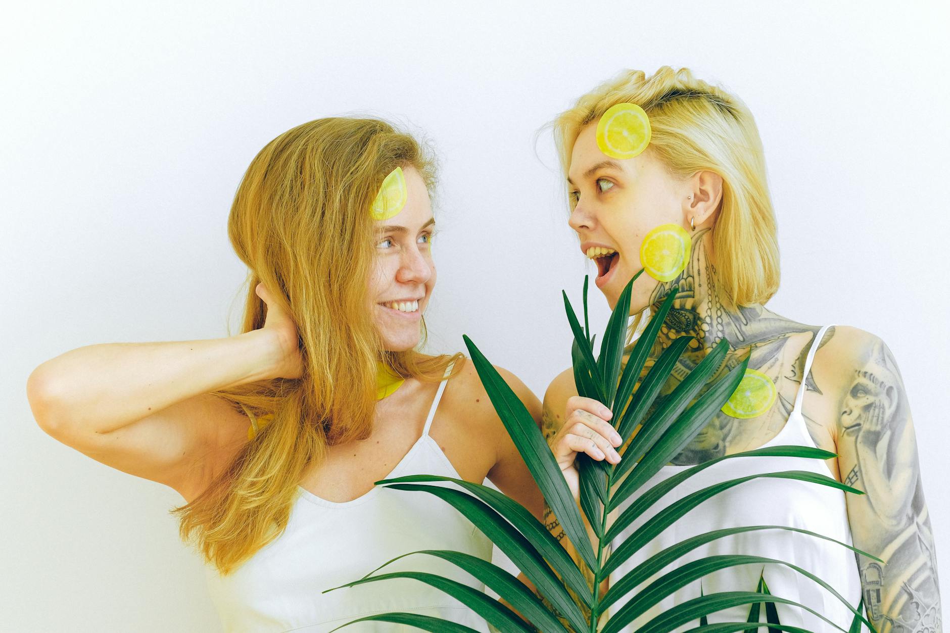 Two women smiling together holding lemons, expressing comfort and joy in intimate conversation