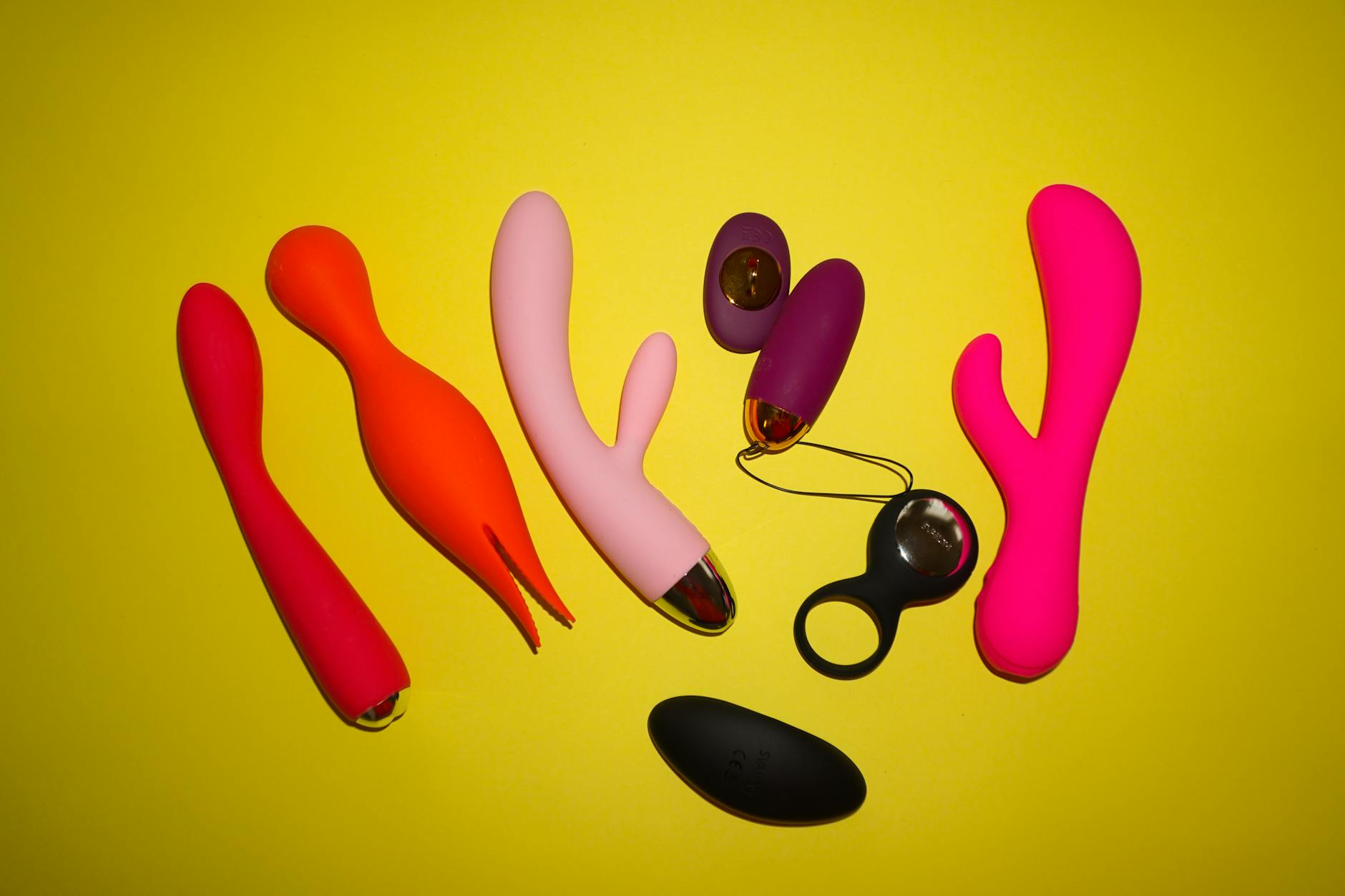 Colorful lemon and other suction vibrators arranged on a bright yellow background